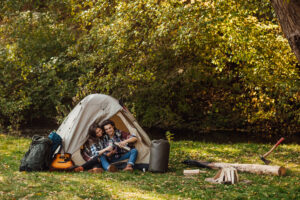 attractive-young-woman-handsome-man-are-spending-time-together-nature-sitting-touristic-tent-forest-drinking-tea